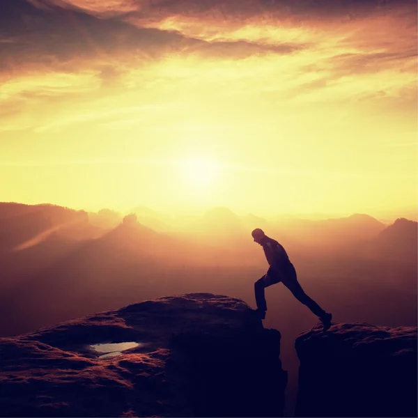 Happy man  jumping between rocks, misty mountains. — Stock Photo, Image