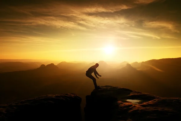 Hombre en negro saltando entre picos. Amanecer de ensueño — Foto de Stock