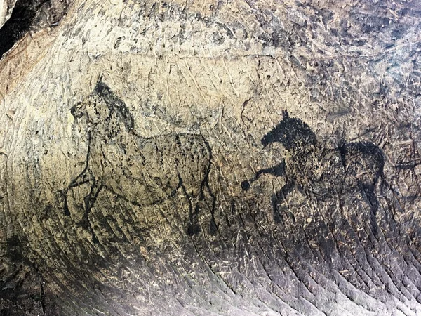 Abstrakte Kinderkunst in der Sandsteinhöhle. schwarze Kohlenstofffarbe von Pferden auf Sandsteinmauer, Kopie eines prähistorischen Bildes. — Stockfoto