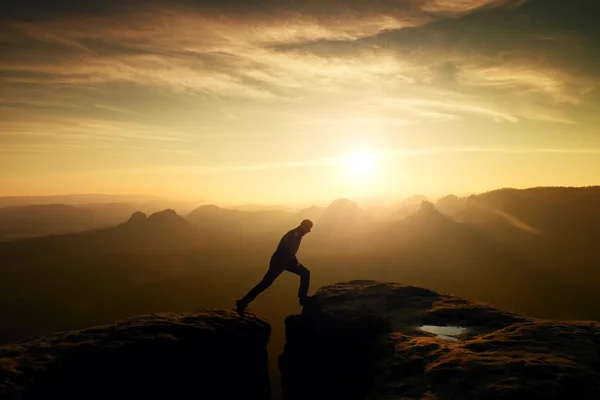 Jumping man. Jonge man maakt stap tussen de kliffen. — Stockfoto