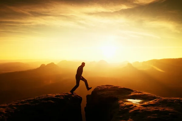 Crazy hiker umping mellan stenar. Underbara färgglada gryning i Klippiga bergen, tunga orange dimma i djupa dalen. Mirakel av naturen — Stockfoto