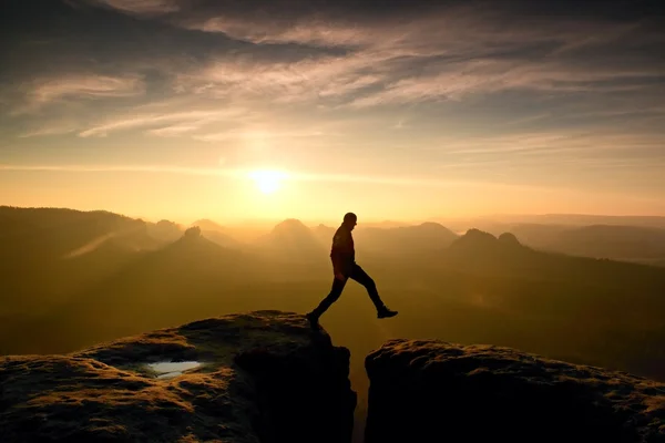 Людина в чорному стрибає між вершинами. Мрійливий денний ранок — стокове фото