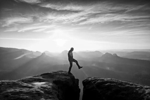 Mann in Schwarz springt zwischen den Gipfeln. verträumter Tagesanbruch — Stockfoto