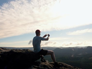 Gri t-shirt ve kırmızı beysbol şapkası turist fotoğraf çeker