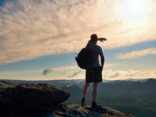 Sendirian turis dengan sporty ransel berdiri di tepi tebing dan menonton ke dalam lembah bellow . — Stok Foto