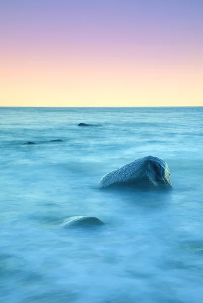 Romantische sfeer in rustige ochtend op zee. Grote keien van soepele golvende zee uitsteekt. Roze horizon — Stockfoto