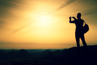 Uzun boylu backpacker telefonu el ile. Bahar daybreak dağlarda.