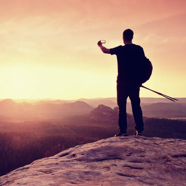 Hombre fuerte excursionista tomando fotos con teléfono inteligente en el pico de la montaña. Maravilloso amanecer . — Foto de Stock