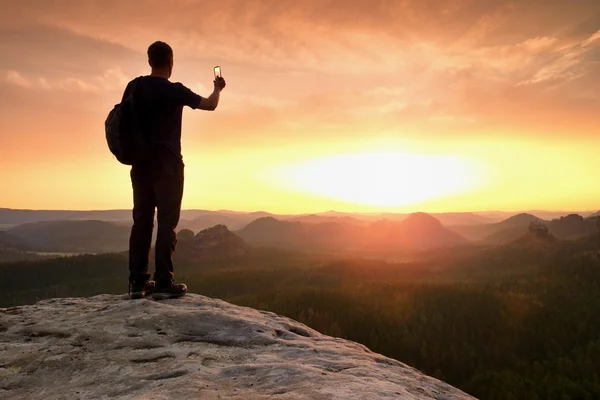 Großer Backpacker mit Handy in der Hand. Frühlingserwachen in den Bergen. — Stockfoto