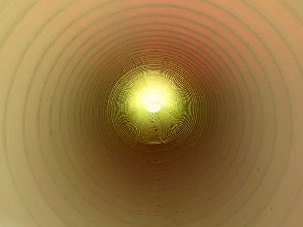 Vue de l'intérieur du long tube en plastique sous terre. Mur côtelé coloré de tuyau en plastique, lumière verte — Photo
