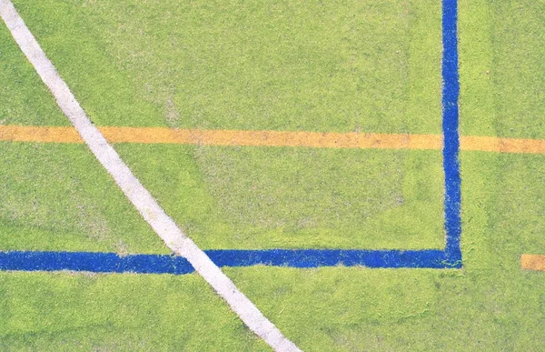 Изношенный пластиковый волосатый ковёр на площадке для игры в ганбол. Пол с красочными линиями маркировки . — стоковое фото