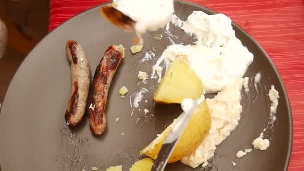 Salsicce alla griglia e patate sono tagliate dacoltello e forchetta in acciaio inossidabile su piatto marrone — Video Stock