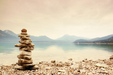 Mavi su dağ Gölü'nün kıyısında taş pyramide dengeli.