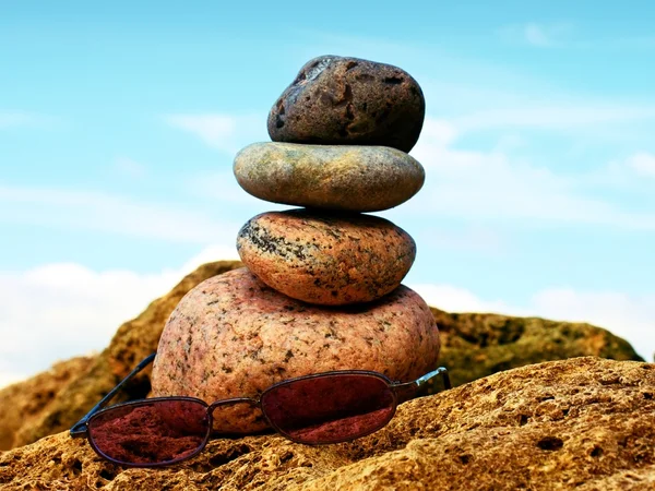 Pink summer glasses and stone pyramid on sea shore — Stock Photo, Image