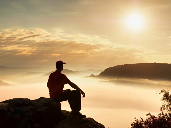 Touristen sitzen auf Felsen. Aussichtspunkt mit Heidekraut und Ästen über nebligem Tal. sonniger Tagesanbruch in den felsigen Bergen. — Stockfoto