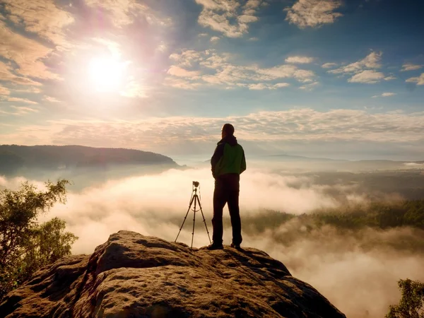 Professioneller Fotograf mit Stativ auf Klippe und Denken. verträumter Nebel — Stockfoto