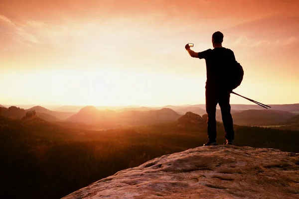 Homem forte caminhante tirar foto com telefone inteligente no pico da montanha. Maravilhoso amanhecer . — Fotografia de Stock