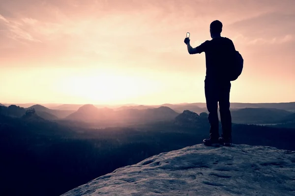 Hiker with backpack on sharp sandstone rock. Foggy valley up to Horizon. — Stock Photo, Image