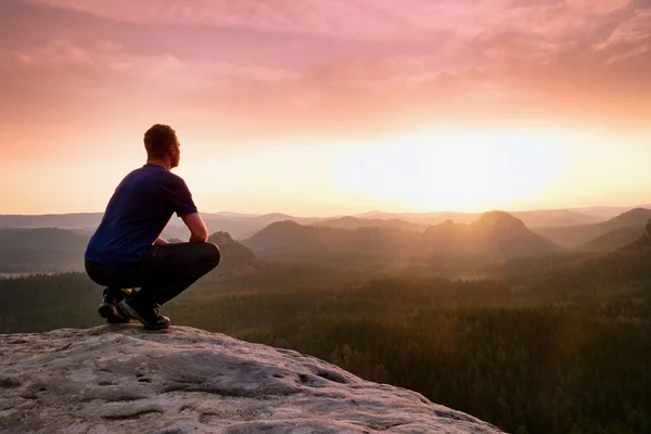 Momento de solidão. Homem sentado no pico da rocha, desfrutar do amanhecer — Fotografia de Stock