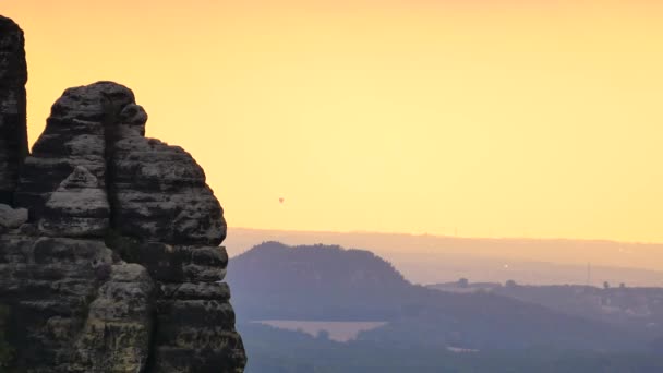 Воздушный шар (воздушный шар), летящий в небе, чтобы спрятаться над острым скалистым пиком. Вечерний закат горный пейзаж, оранжевое небо и воздух с высокой влажностью . — стоковое видео