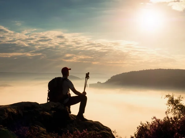 Tourist  with trekking poles and big backpack on rock. Heavy creamy mist — Stock Photo, Image