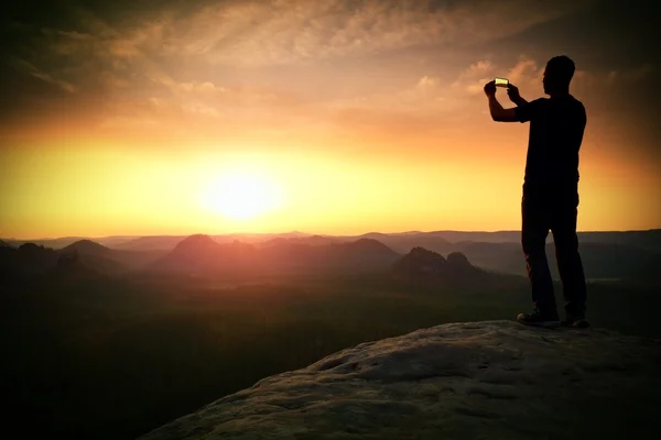 Tall hiker is taking photo by smartphone on mountain — Stock Photo, Image