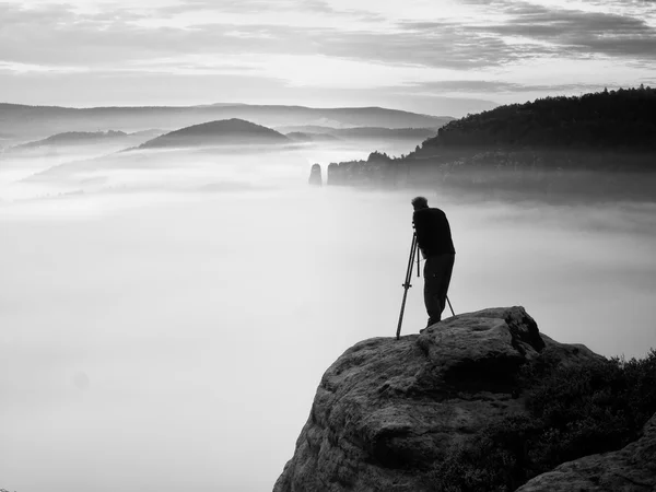 Konstnären fotograf med stativ på cliff arbete — Stockfoto