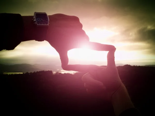 Закройте руки с помощью часов, делая жесты рамы. Темная туманная долина, окутанная пейзажем . — стоковое фото