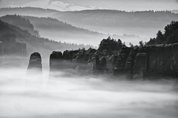 Fantastique lever de soleil sur le sommet de la montagne rocheuse avec vue sur la vallée brumeuse. Photo noir et blanc — Photo