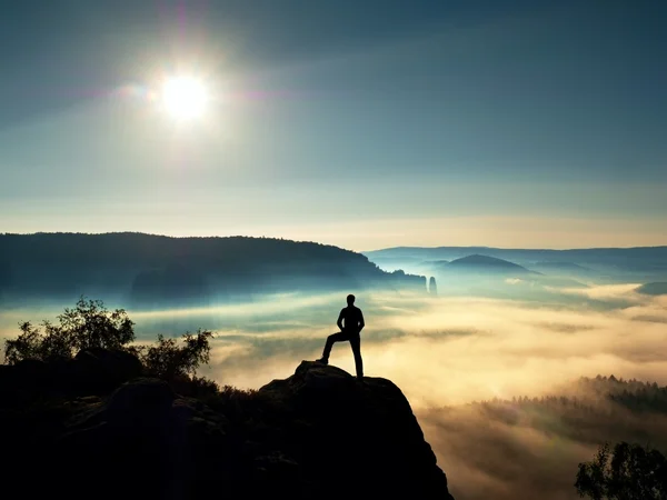 Man silhouette on the sharp peak. Satisfy hiker enjoy view. Tall man on the peak of cliff watching down to landscape. Vivid and strong vignetting effect. — Stock Photo, Image