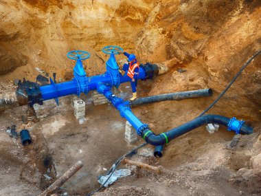 Worker underground at  gate valve on drink water system, waga multi joint members. clipart