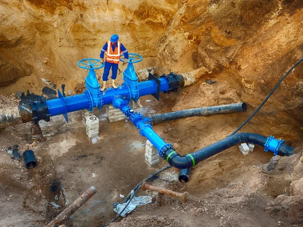 Trabajador subterráneo en la válvula de compuerta en el sistema de agua potable, waga varios miembros conjuntos . Imágenes de stock libres de derechos