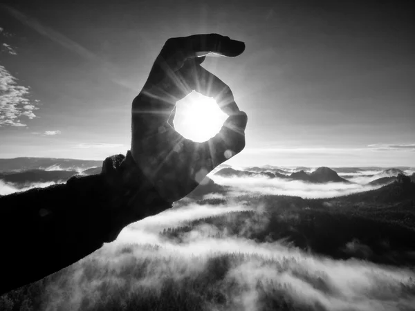 Mann mit der Hand die Sonne berühren. nebliger Tagesanbruch in einer schönen Hügellandschaft. — Stockfoto