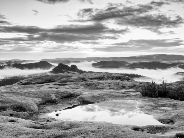 Schwarz-Weiß-Foto. nebliger Tagesanbruch in einem wunderschönen Hügelland. Berggipfel ragen aus nebligem Hintergrund. — Stockfoto