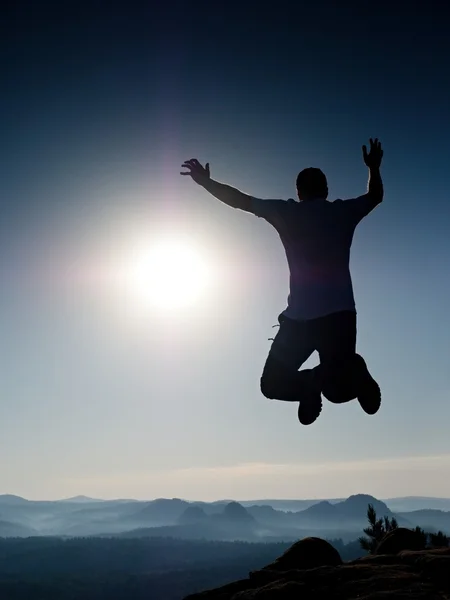 Jovem louco está pulando no pico da montanha. Silhueta de homem de salto — Fotografia de Stock