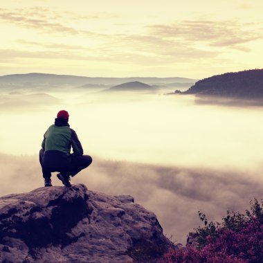Kırmızı bere ve spor kayada çömelme konumda turist