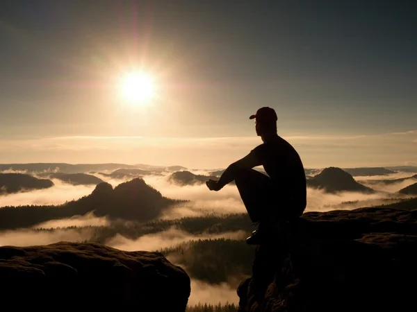 Moment van eenzaamheid. Man met GLB sit op berg en horloge te mist — Stockfoto