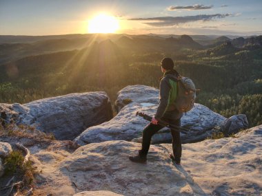 Kameralı bir adam gün batımında bir tepede fotoğraf çekiyor ve gökyüzünü bulanıklaştırıyor. Soyut filtre.
