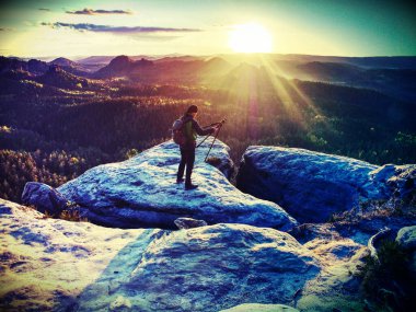 Lens fişeği. Zirvedeki turist rehberi fotoğraf çekiyor. Sırt çantalı güçlü bir yürüyüşçü. Soyut filtre.