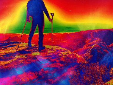 Bacağı yaralanmış bir adam koltuk değneklerine yaslanıyor uçurumun kenarında duruyor ve gün batımında manzarayı seyrediyor. Soyut filtre.