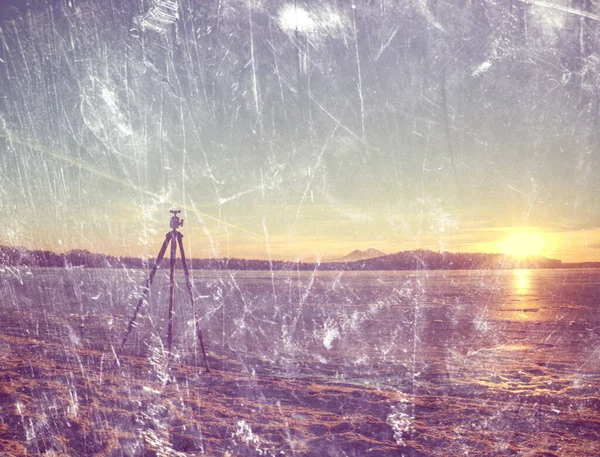 日落时冰封在冰封的湖上 摄影记者三脚架在岸上 深浅的田野 抽象过滤器 — 图库照片