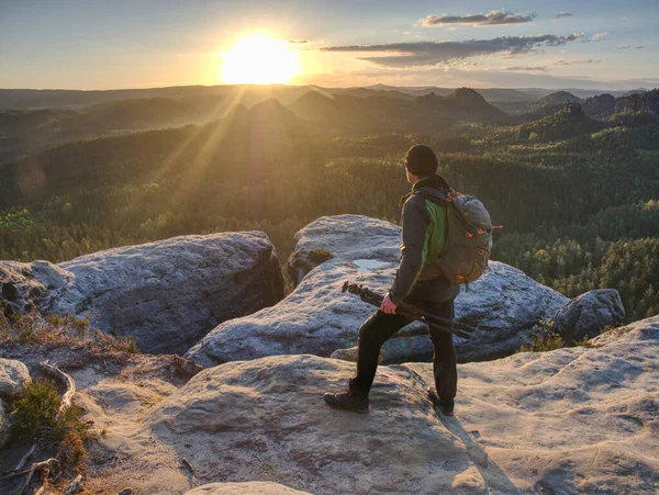 Kameralı bir adam gün batımında bir tepede fotoğraf çekiyor ve gökyüzünü bulanıklaştırıyor. Soyut filtre.