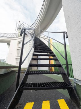 Bir fabrikadaki kaçış çıkışının dış merdivenleri. Zemindeki sarı işaretler güvenliğe giden en kısa yolu gösteriyor..