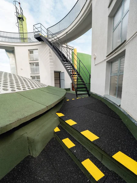 Outdoor stairs of an escape exit in a factory. Yellow markings on the floor show the shortest way to safety.