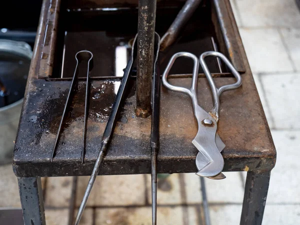 Shaped Blowing Glass Diamond Shear Scissors on a Metal Table. Detailed glassblower tools in workshop