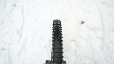 Kaygan karlı yolda Fatbike ön tekerlek sürüyor. Kışın yavaş hareket eden bisiklet. Dönen tekerlek ve yüksek bujili lastik izleri. Ekstrem sporlar.