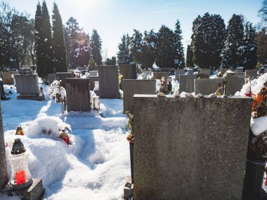 Karla kaplı bir mezarlıktaki mezar taşları. Sessiz bir yer. Parlayan mum daha sonra.