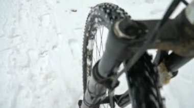 MTB 'nin ön tekerleği, çiğnenmiş ve donmuş karda sert ve beceriksizce döner. Dağ bisikleti üzerinde kış eğitimi, orman yolu..