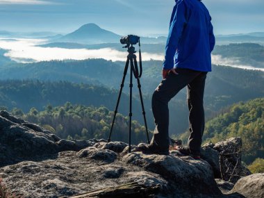 Sabah güneş ışınları bulutların arasından geçer ve insan tripodda kamera ve telekom mercekleriyle kalıp kompozisyonu düşünür. Sonbahar sisli manzarası.