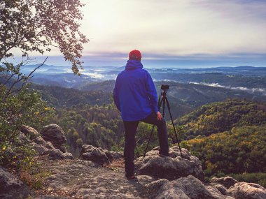 Sabah güneş ışınları bulutların arasından geçer ve insan tripodda kamera ve telekom mercekleriyle kalıp kompozisyonu düşünür. Sonbahar sisli manzarası.